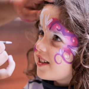 Maquilleuse professionnelle réalisant un maquillage de fête sur le visage d’un enfant