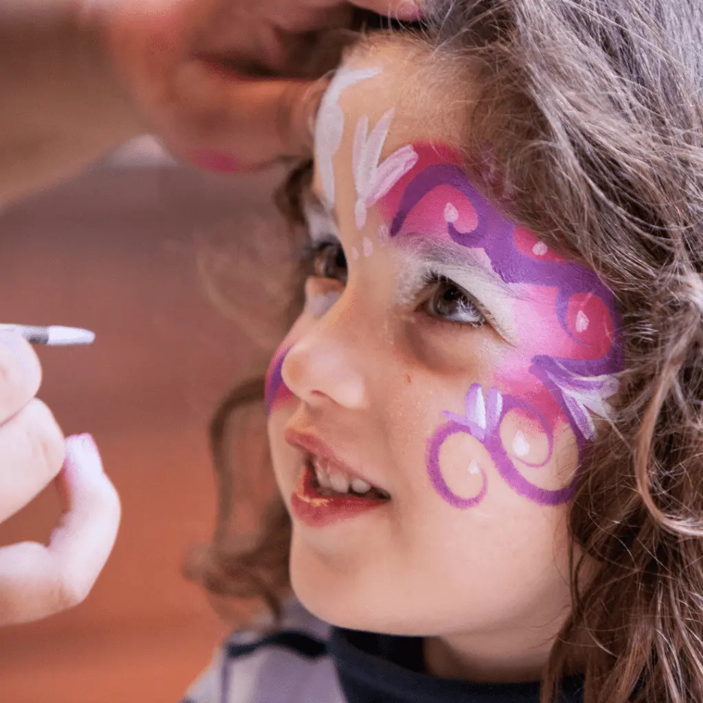 Maquilleuse professionnelle réalisant un maquillage de fête sur le visage d’un enfant